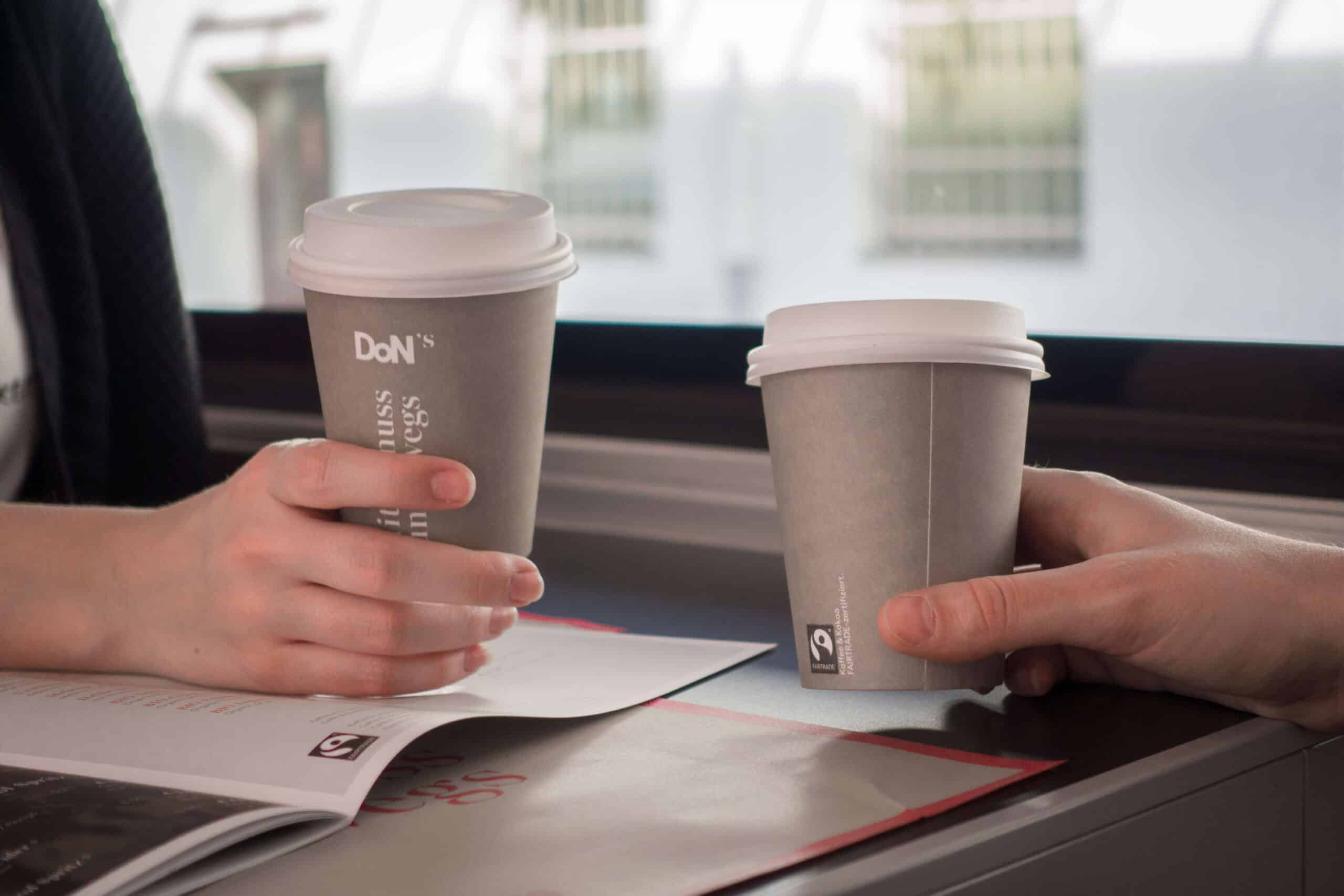 Zwei Händemit Kaffeebechern auf denen das Fairtrade-Logo zu sehen ist