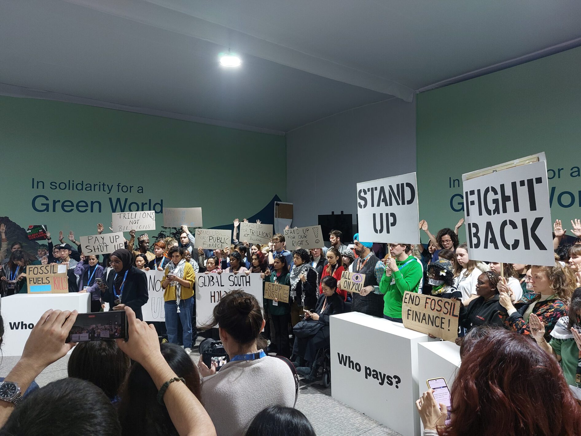 Menschen protestieren mit Schildern bei der COP29 in Baku